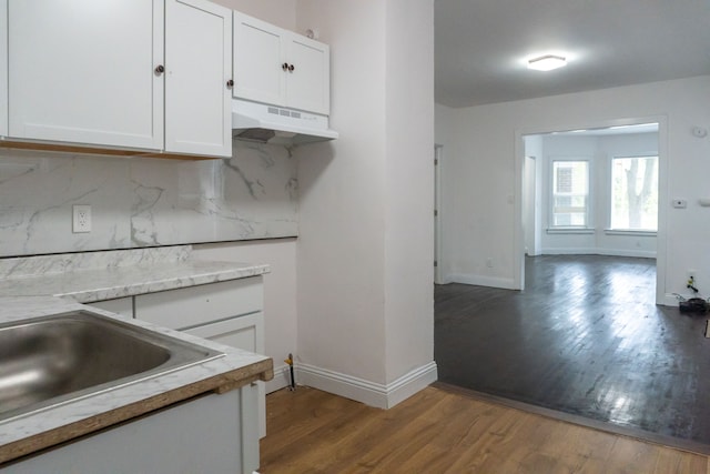 kitchen with hardwood / wood-style floors, tasteful backsplash, white cabinetry, and sink