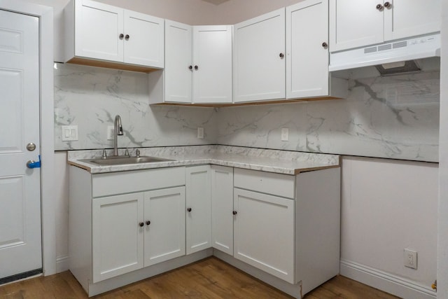 kitchen with backsplash, white cabinetry, sink, and wood-type flooring