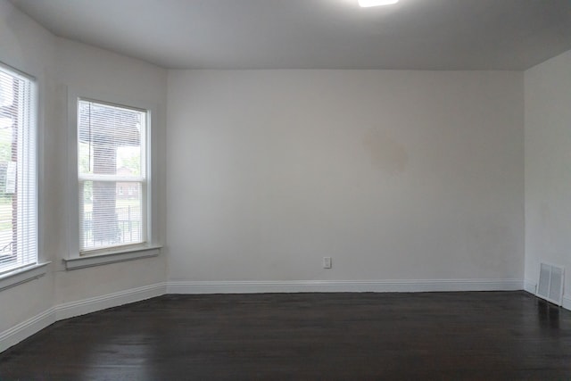 empty room featuring dark hardwood / wood-style flooring and a wealth of natural light