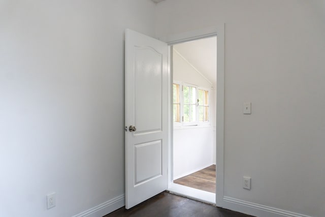 spare room featuring dark hardwood / wood-style flooring and lofted ceiling