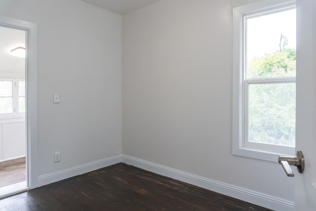 unfurnished room with dark hardwood / wood-style flooring and a healthy amount of sunlight