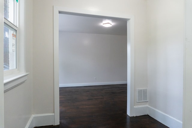 empty room featuring a healthy amount of sunlight and dark hardwood / wood-style floors