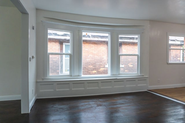 empty room with plenty of natural light and dark wood-type flooring