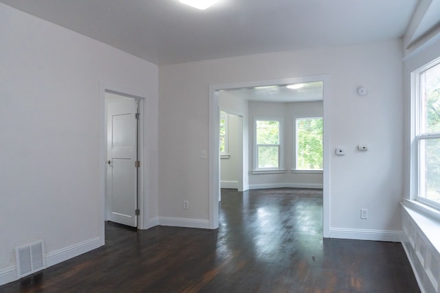 spare room featuring a healthy amount of sunlight and dark hardwood / wood-style flooring