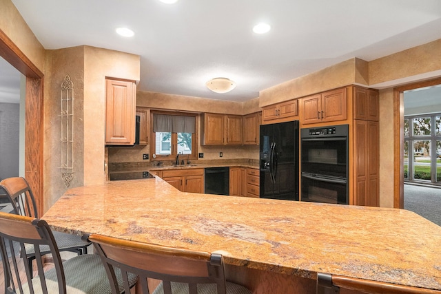 kitchen with black appliances, a kitchen breakfast bar, kitchen peninsula, and sink