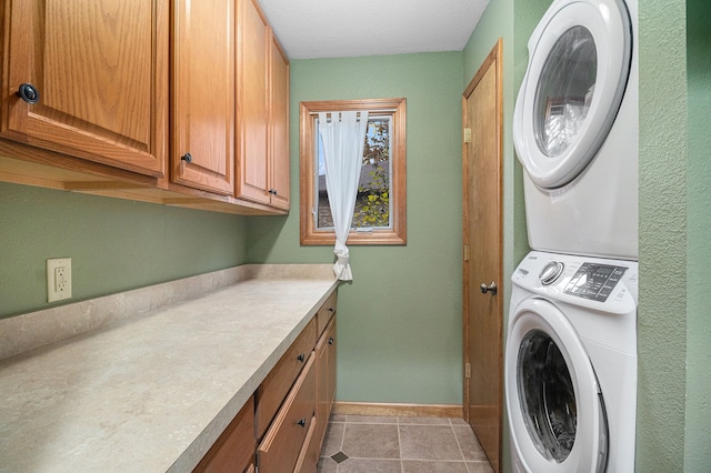 laundry room featuring cabinets, stacked washing maching and dryer, and light tile patterned floors