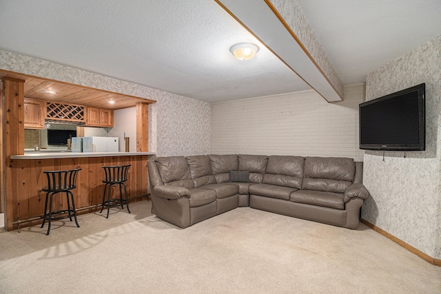 living room with light carpet, bar area, a textured ceiling, and beamed ceiling