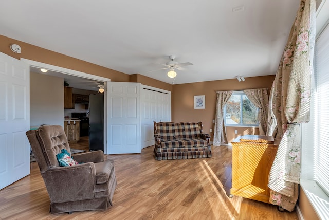 sitting room with ceiling fan and wood-type flooring