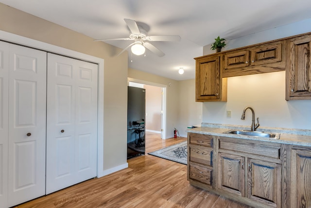 kitchen featuring ceiling fan, sink, and light hardwood / wood-style floors