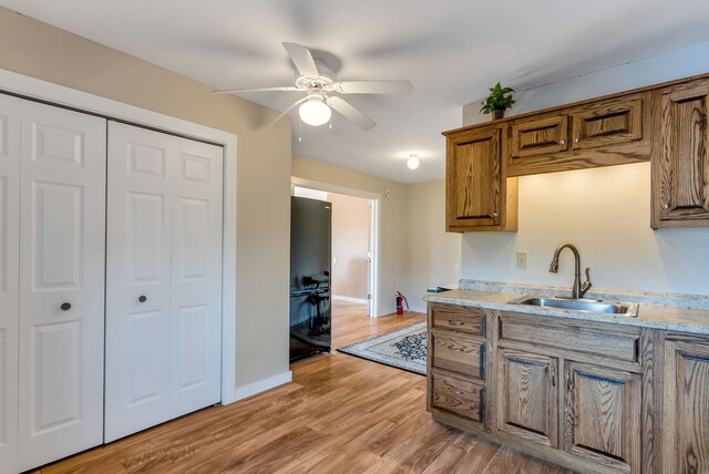 381 S Lorenz Rd, Tawas City, MI 48763 - kitchen with a sink, freestanding refrigerator, brown cabinetry, light wood-style flooring, and a ceiling fan