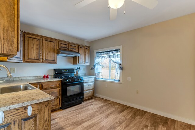 381 S Lorenz Rd, Tawas City, MI 48763 - kitchen with gas stove, under cabinet range hood, a sink, brown cabinetry, and light countertops