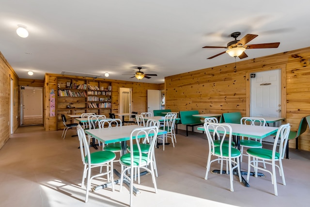 dining room with wood walls and ceiling fan