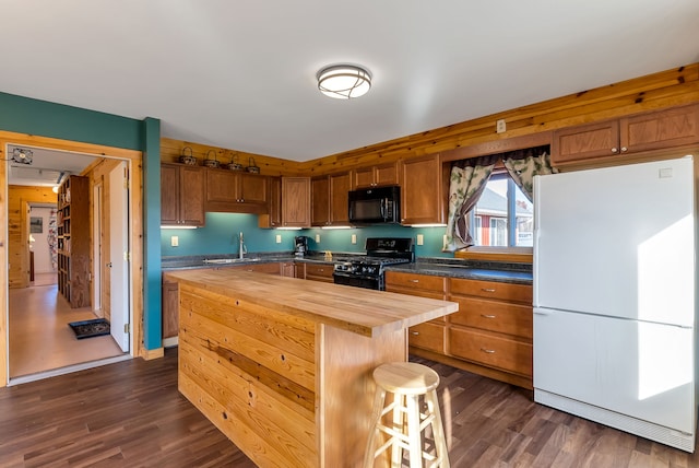 kitchen with wooden counters, dark hardwood / wood-style flooring, a center island, and black appliances