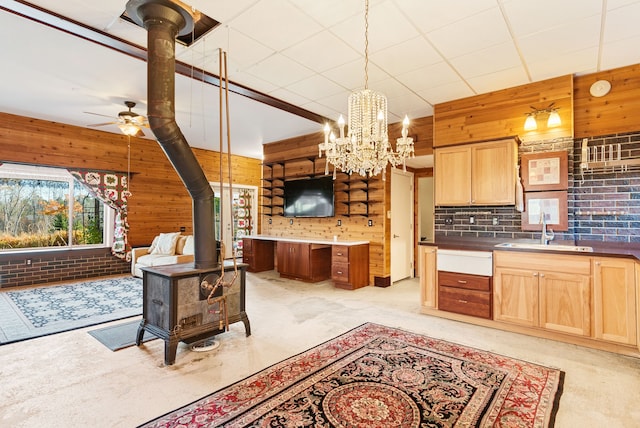 kitchen with plenty of natural light, wood walls, a wood stove, and sink