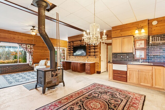 381 S Lorenz Rd, Tawas City, MI 48763 - kitchen with a wood stove, a sink, wood walls, light brown cabinets, and a ceiling fan