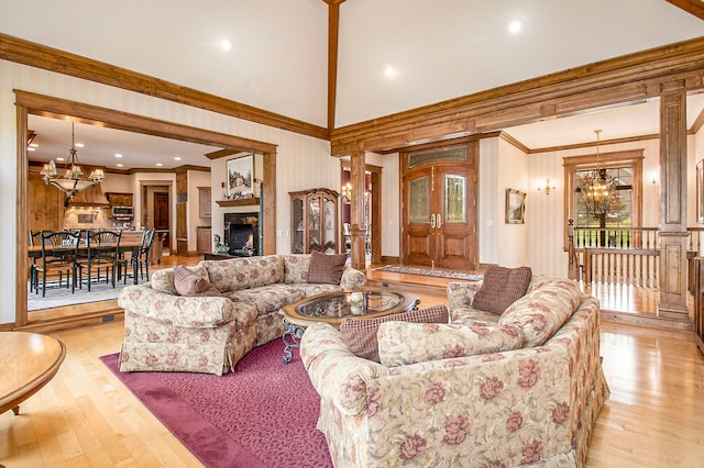 living room with crown molding, light hardwood / wood-style flooring, high vaulted ceiling, and an inviting chandelier