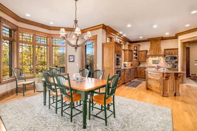 dining space with ornamental molding, a notable chandelier, and light wood-type flooring