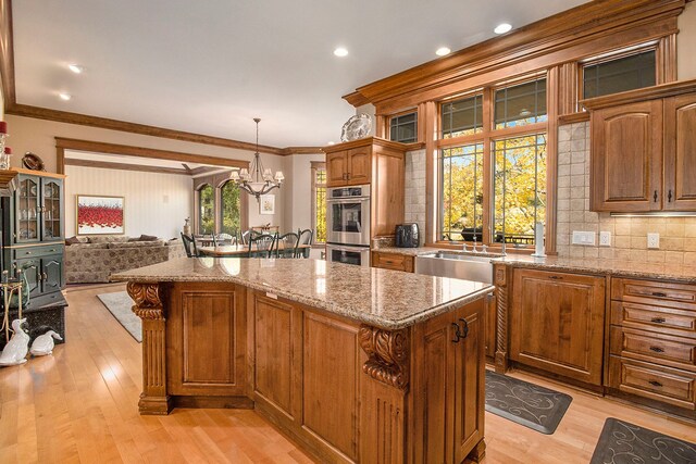 kitchen featuring a center island, stainless steel double oven, hanging light fixtures, and a notable chandelier