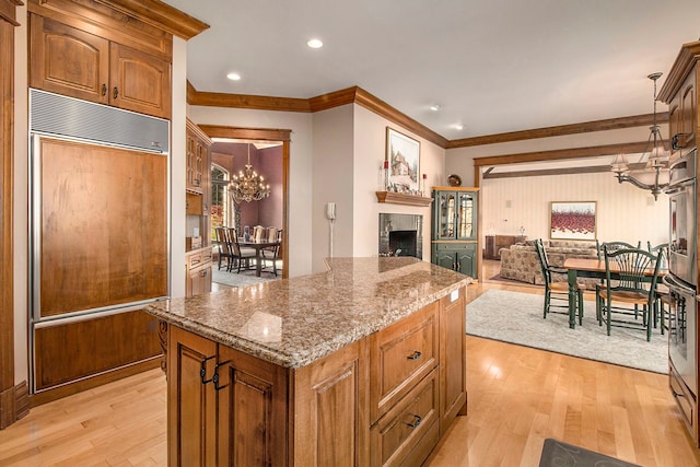 kitchen featuring paneled fridge, pendant lighting, light hardwood / wood-style flooring, stone counters, and a kitchen island