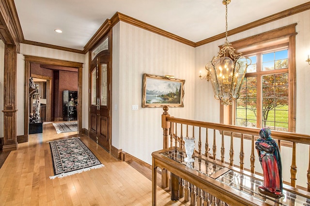 hall with a chandelier, hardwood / wood-style floors, a wealth of natural light, and ornamental molding