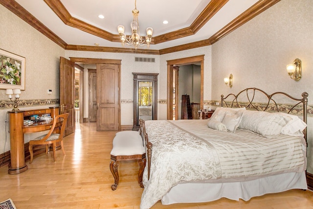 bedroom with a tray ceiling, a chandelier, ornamental molding, and light wood-type flooring