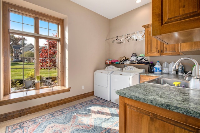 laundry area with a healthy amount of sunlight, washing machine and dryer, light tile patterned floors, and sink