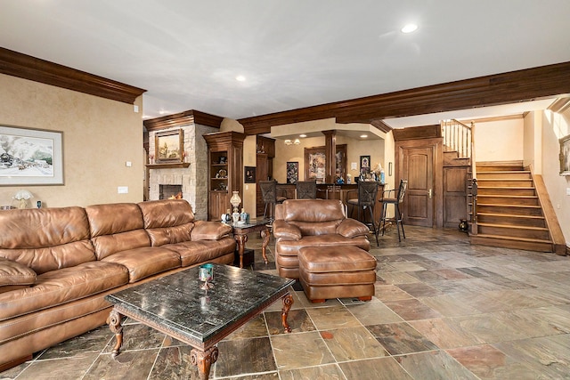 living room with a fireplace, ornate columns, and crown molding