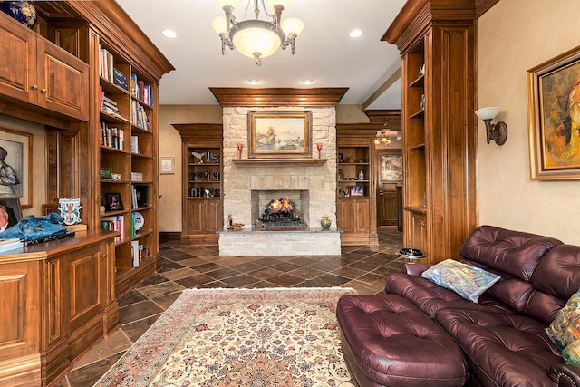 living room featuring built in shelves, a stone fireplace, and a notable chandelier