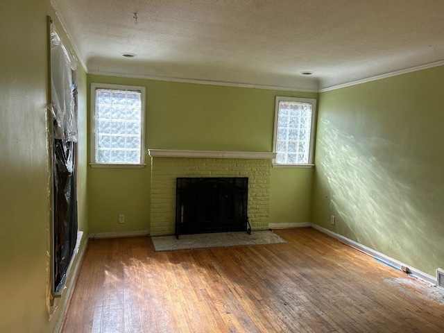 unfurnished living room with plenty of natural light, crown molding, wood-type flooring, and a fireplace