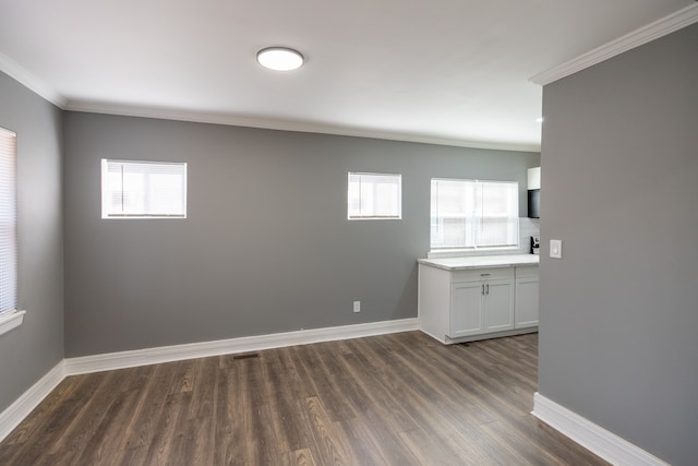 unfurnished room featuring a healthy amount of sunlight, ornamental molding, and dark wood-type flooring