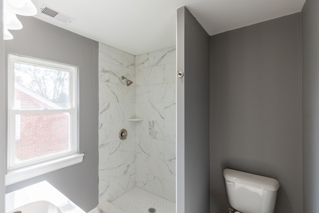 bathroom featuring toilet and a tile shower