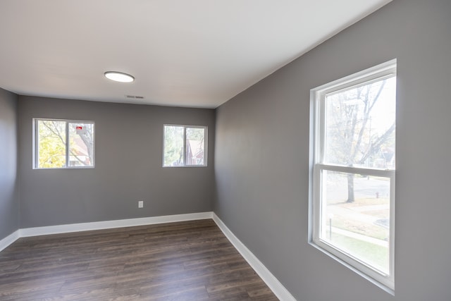 empty room with dark hardwood / wood-style floors and plenty of natural light