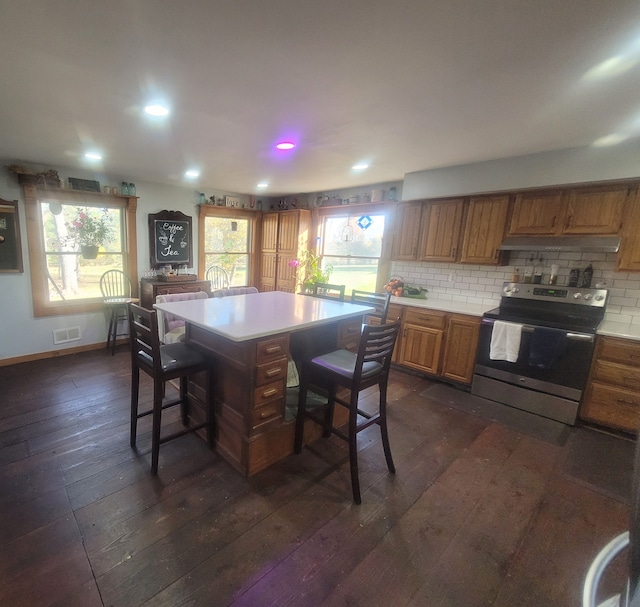 kitchen featuring electric stove, tasteful backsplash, dark hardwood / wood-style floors, a center island, and a kitchen breakfast bar