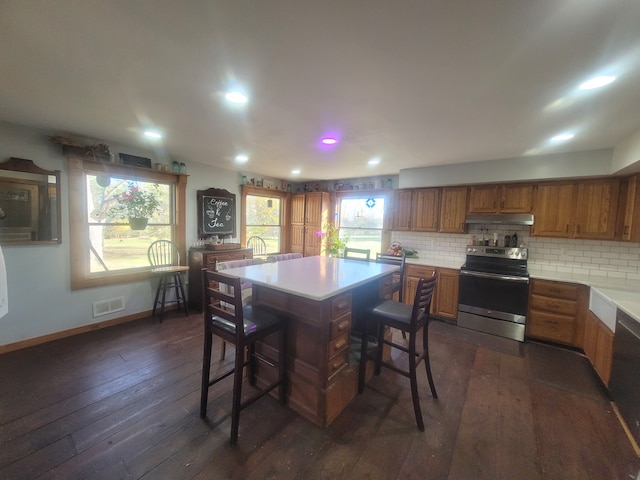 kitchen featuring backsplash, a kitchen island, a kitchen bar, dark wood-type flooring, and stainless steel electric stove