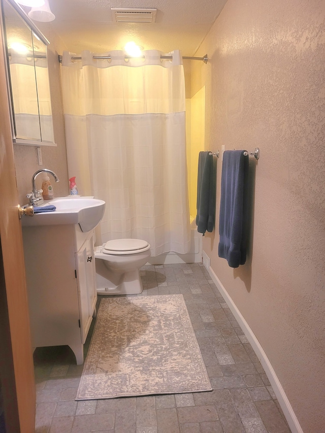 bathroom with toilet, vanity, walk in shower, and a textured ceiling