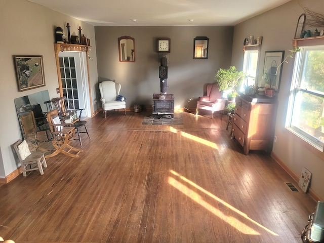 living room with dark hardwood / wood-style floors, a wealth of natural light, and a wood stove