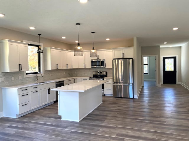 kitchen featuring hanging light fixtures, a kitchen island, a healthy amount of sunlight, and appliances with stainless steel finishes