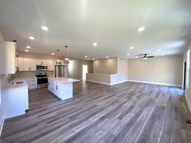 kitchen with white cabinets, dark hardwood / wood-style floors, a kitchen island, and stainless steel appliances