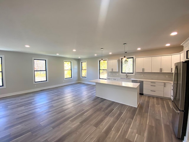 kitchen featuring a center island, stainless steel appliances, white cabinetry, and a wealth of natural light