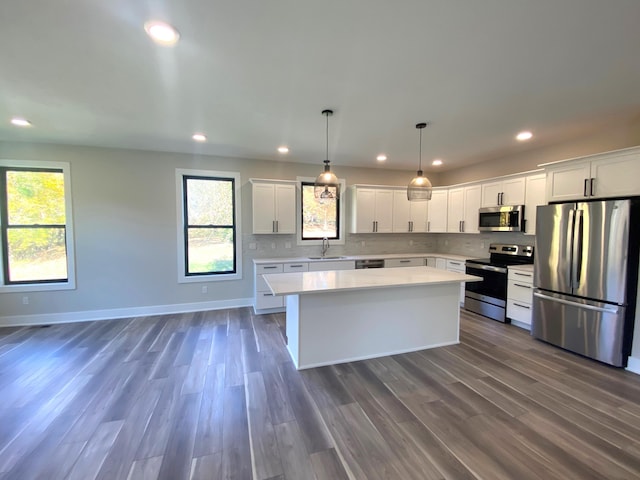 kitchen with sink, decorative light fixtures, a kitchen island, dark hardwood / wood-style flooring, and stainless steel appliances