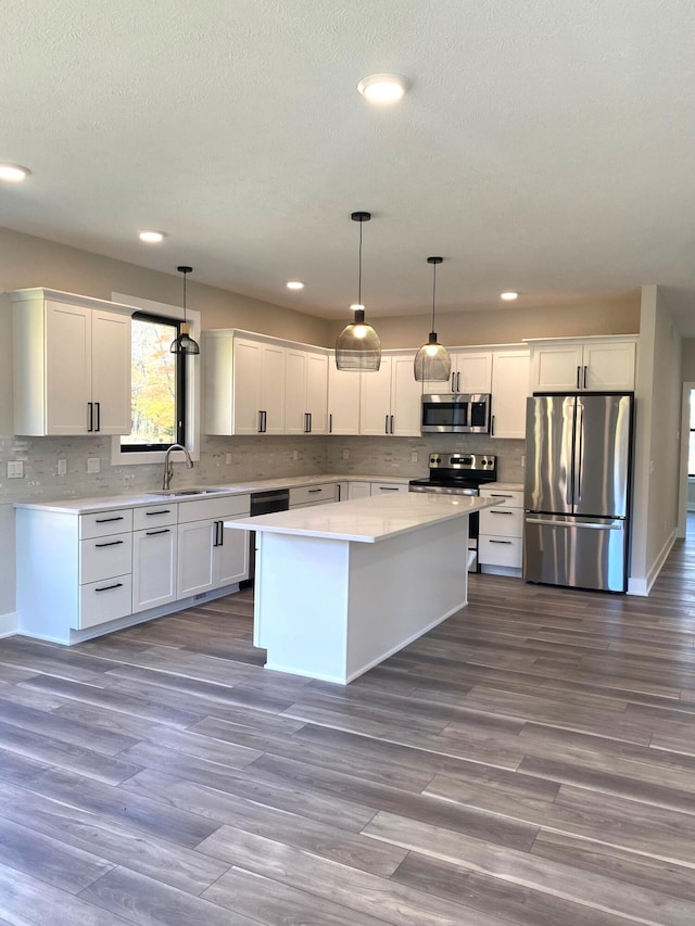 kitchen with white cabinetry, a center island, hanging light fixtures, and appliances with stainless steel finishes