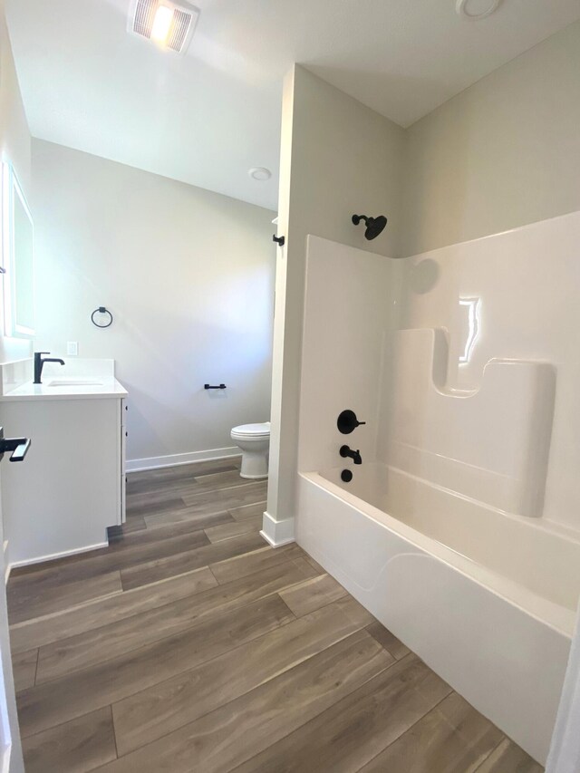 7480/7482 Head Rd, Delton, MI 49046 - bathroom with toilet, vanity, wood finished floors, and shower / bathtub combination