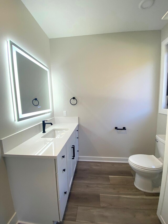 7480/7482 Head Rd, Delton, MI 49046 - half bath with toilet, vanity, wood finished floors, and baseboards