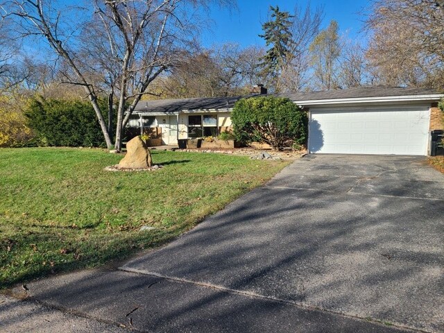 single story home featuring a garage and a front lawn