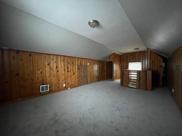 additional living space featuring lofted ceiling, carpet floors, and wooden walls