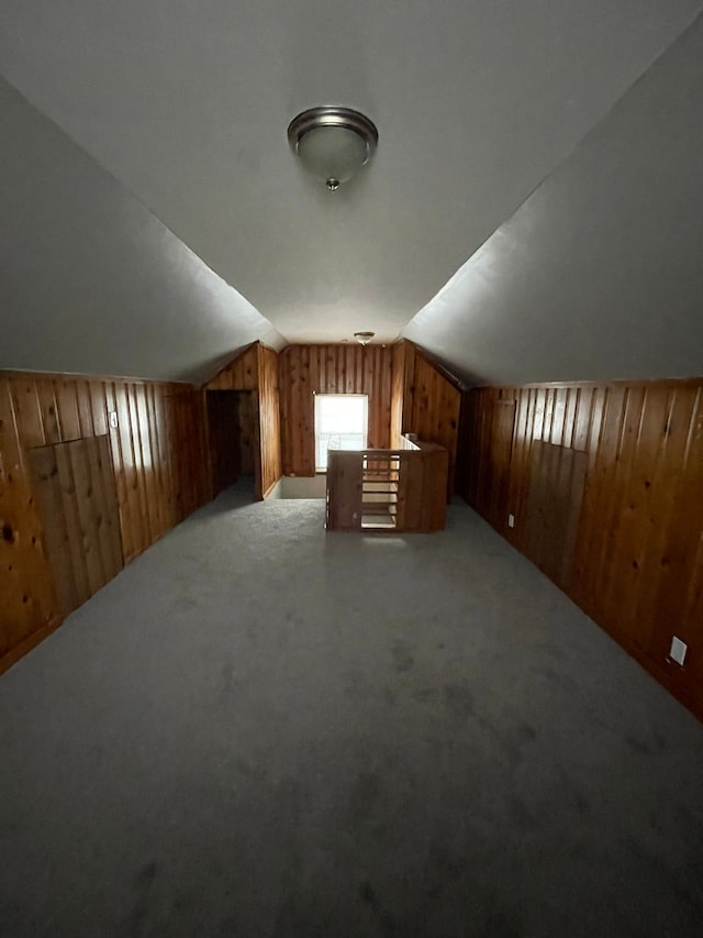 additional living space with wood walls, light carpet, and vaulted ceiling