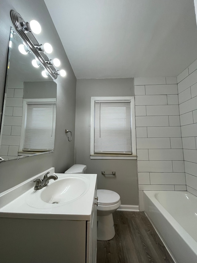 full bathroom with vanity, wood-type flooring, tiled shower / bath combo, and toilet