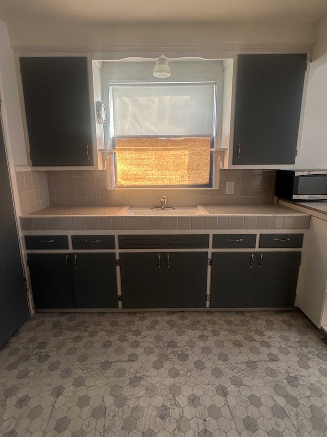 kitchen with tasteful backsplash, tile counters, and sink