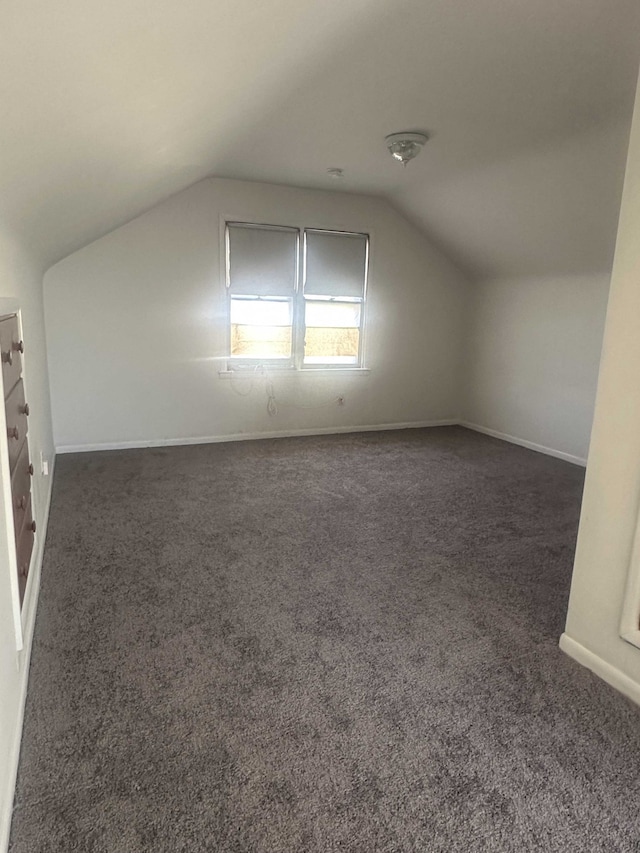 bonus room with dark carpet and vaulted ceiling