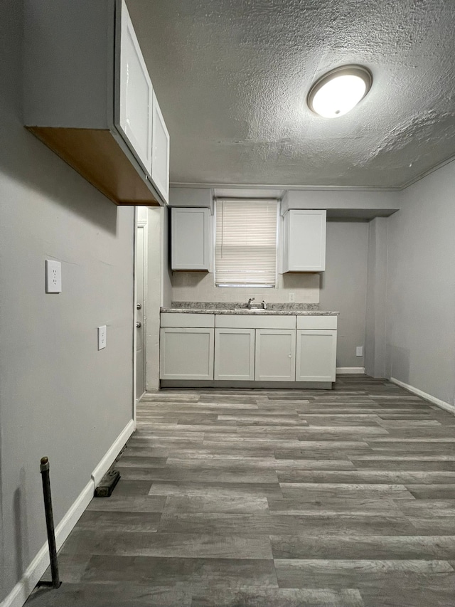 kitchen featuring hardwood / wood-style floors, white cabinetry, and a textured ceiling